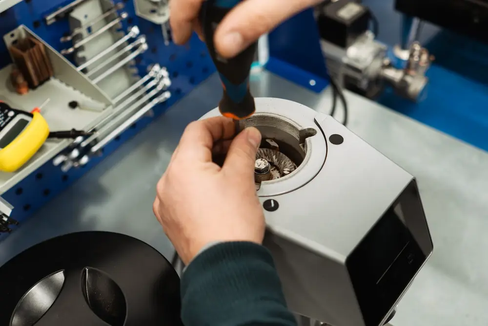 Engineer working on a machined aluminium housing at a workbench, hand tools racked behind